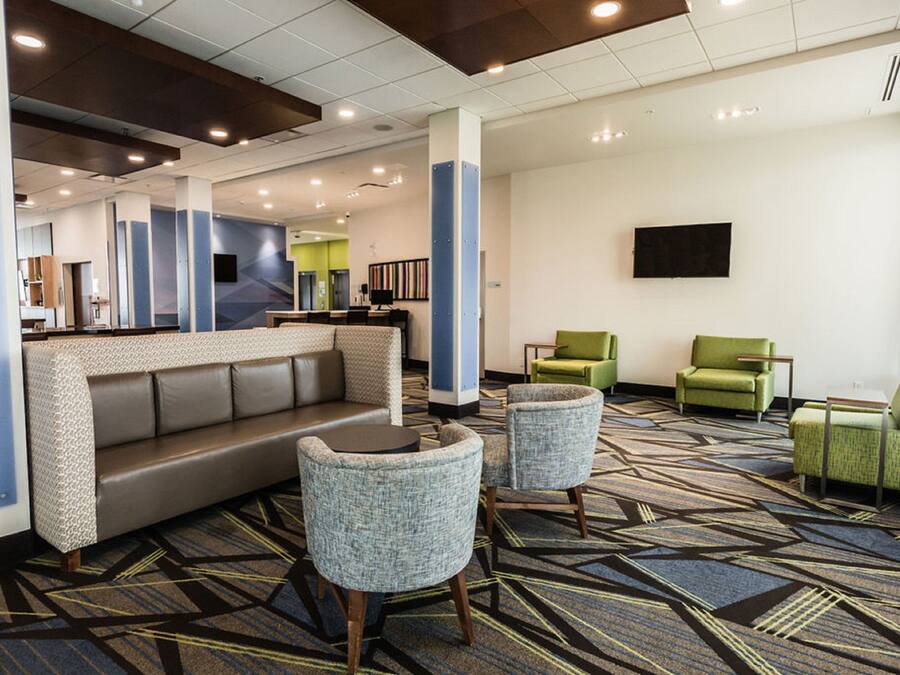 A lobby with a reception desk, a sofa, two armchairs, and a television mounted on the wall.