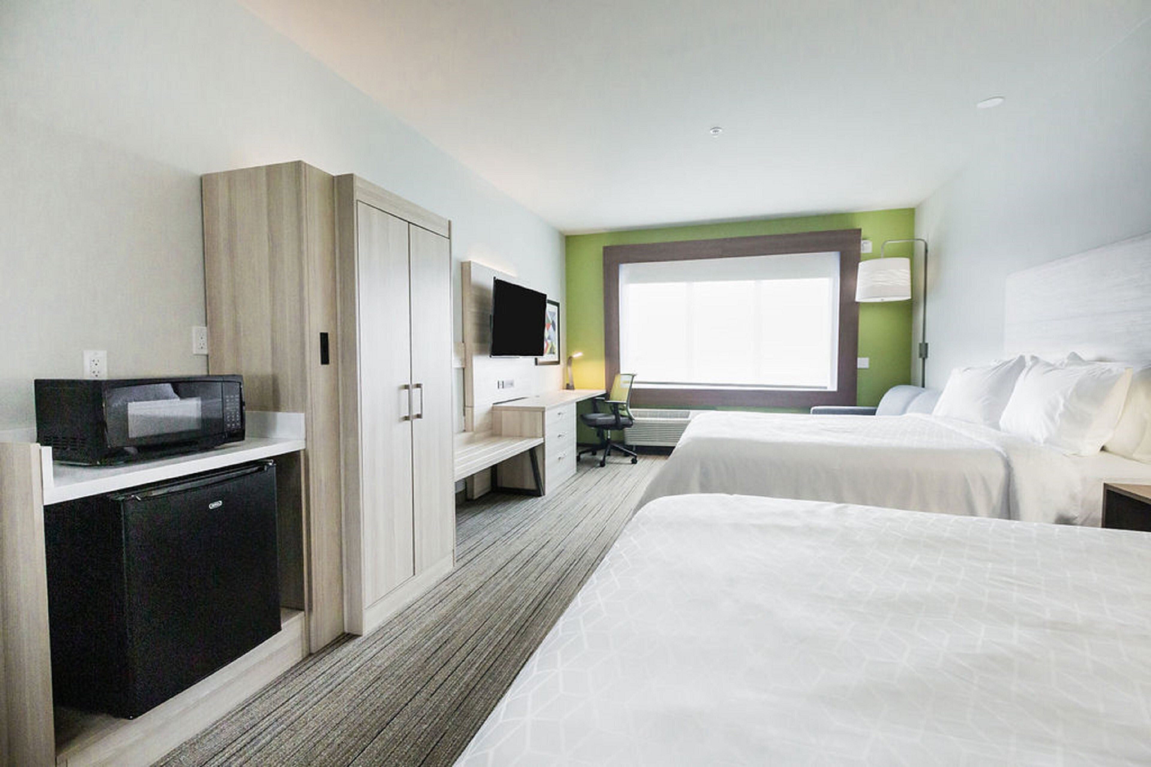 Una habitación de hotel con dos camas, un escritorio, un microondas y un televisor.