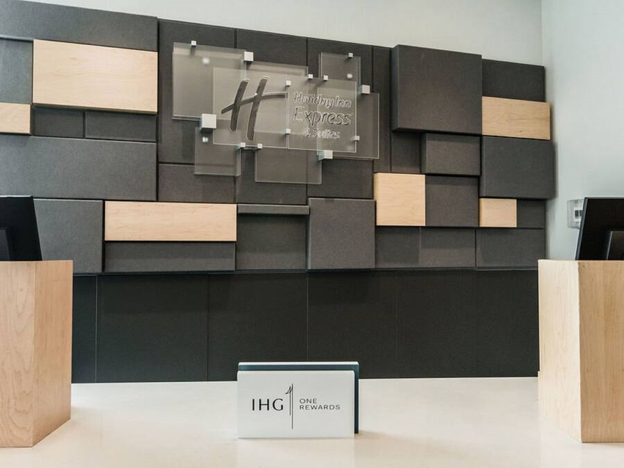 A reception desk with a modern design, featuring a mix of dark and light wood panels. A sign above the desk reads "Holiday Inn Express & Suites."