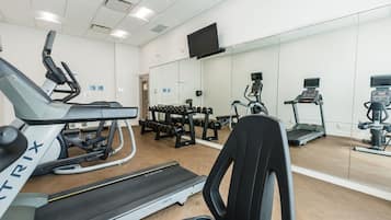 A gym with treadmills, dumbbells, and exercise equipment.