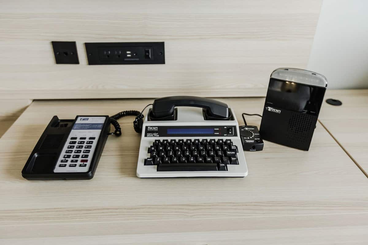 A desk with a telephone, a keyboard, and a speaker.