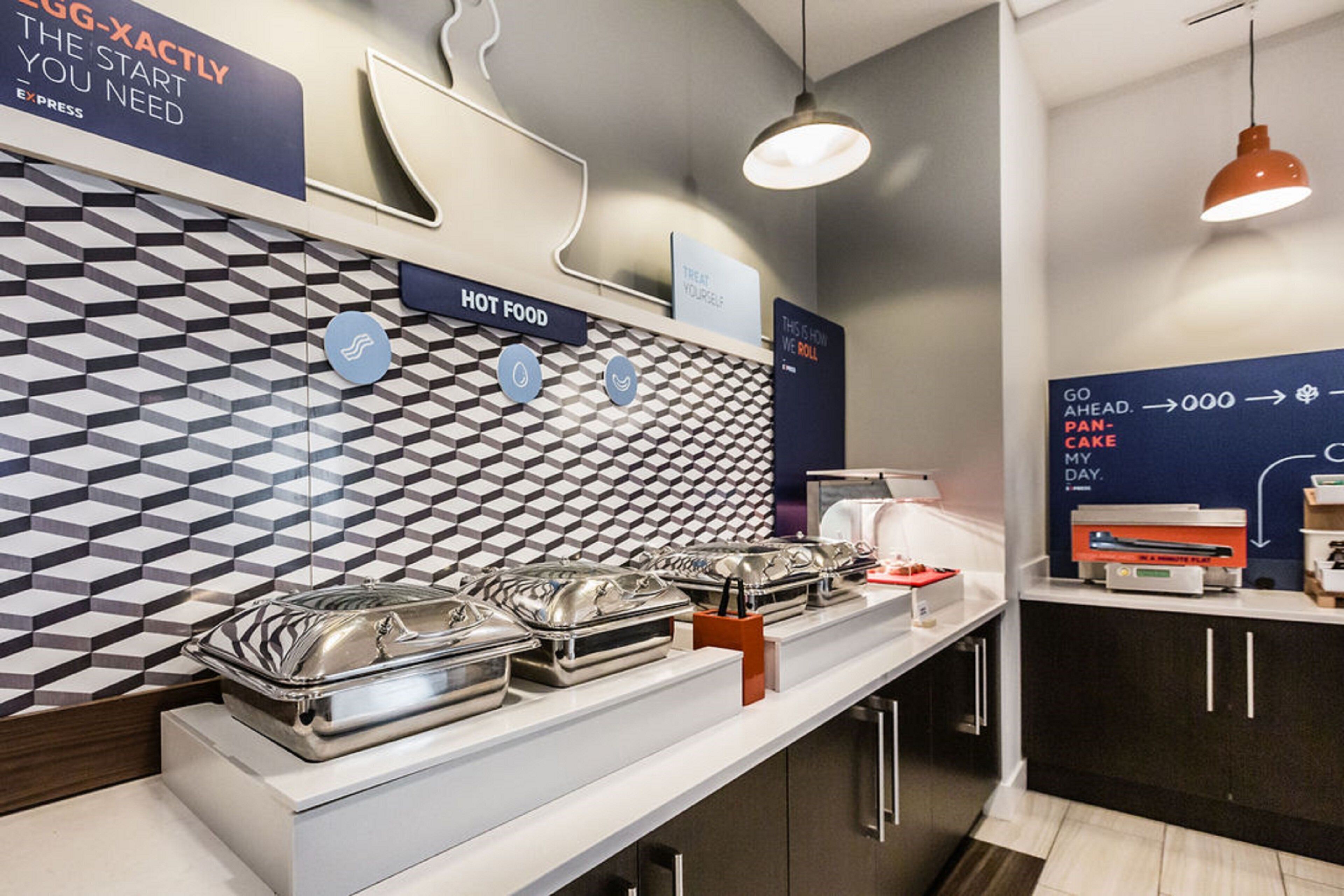 A buffet setup with multiple serving stations, a patterned wall, and a counter with a coffee machine.