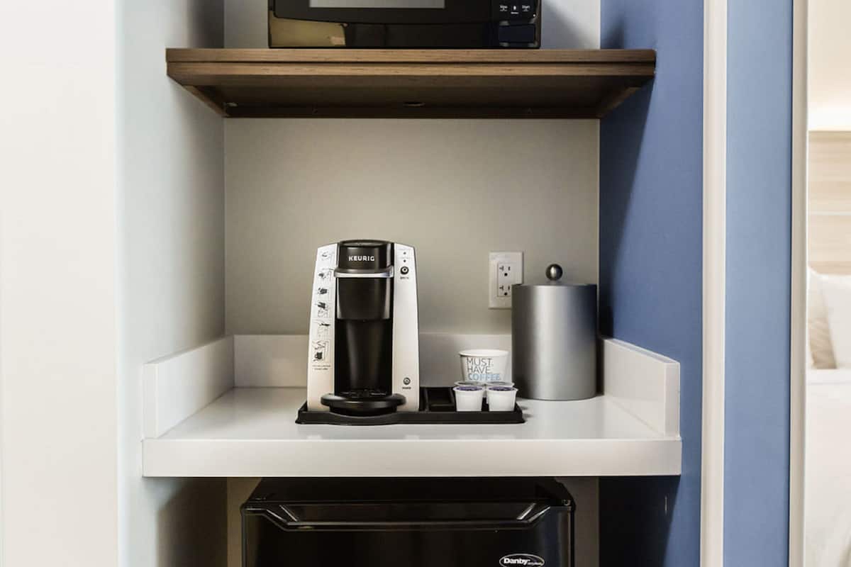A coffee machine on a white countertop with a coffee pod holder and a cup of coffee.