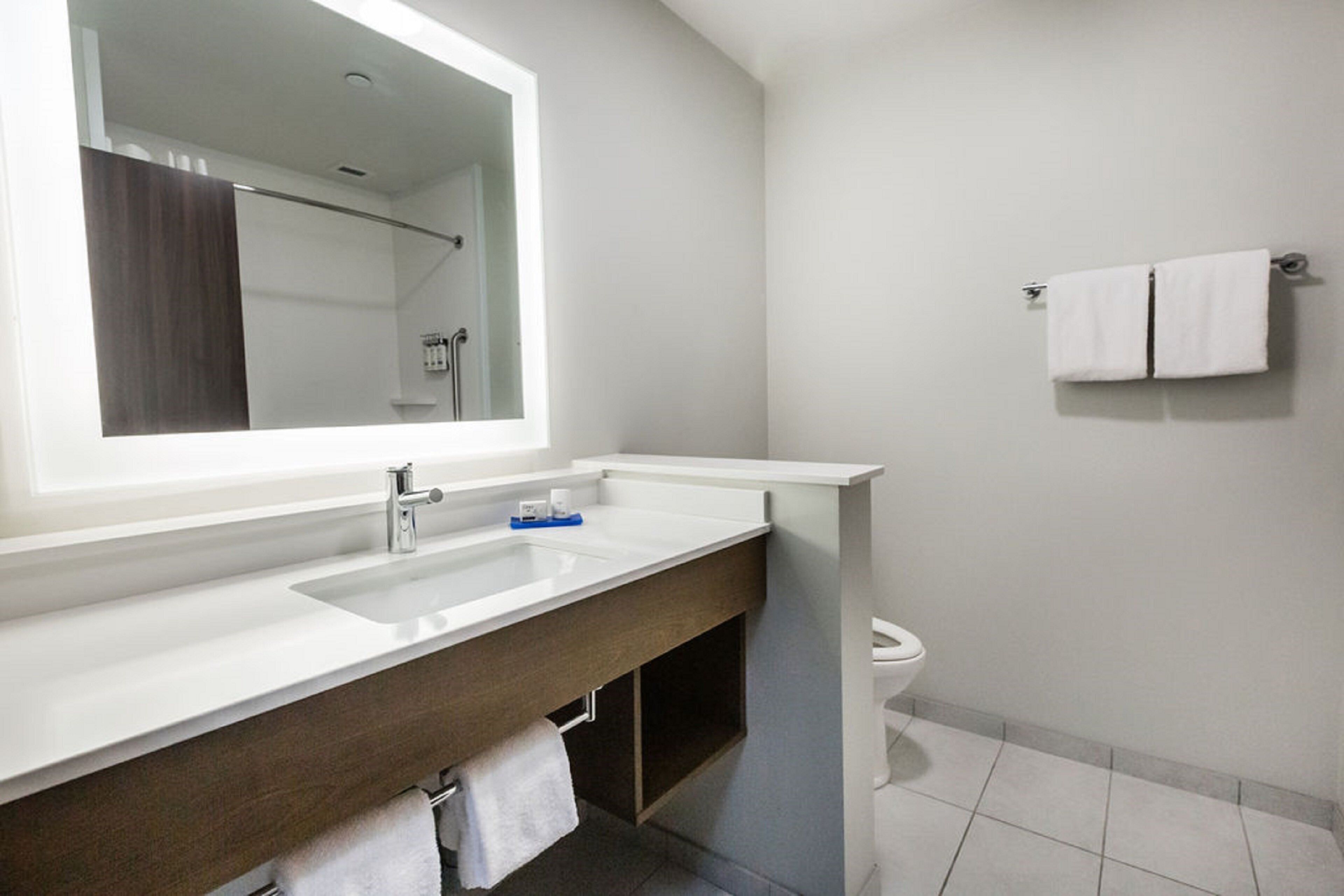 A modern bathroom with a white sink, mirror, and toilet.