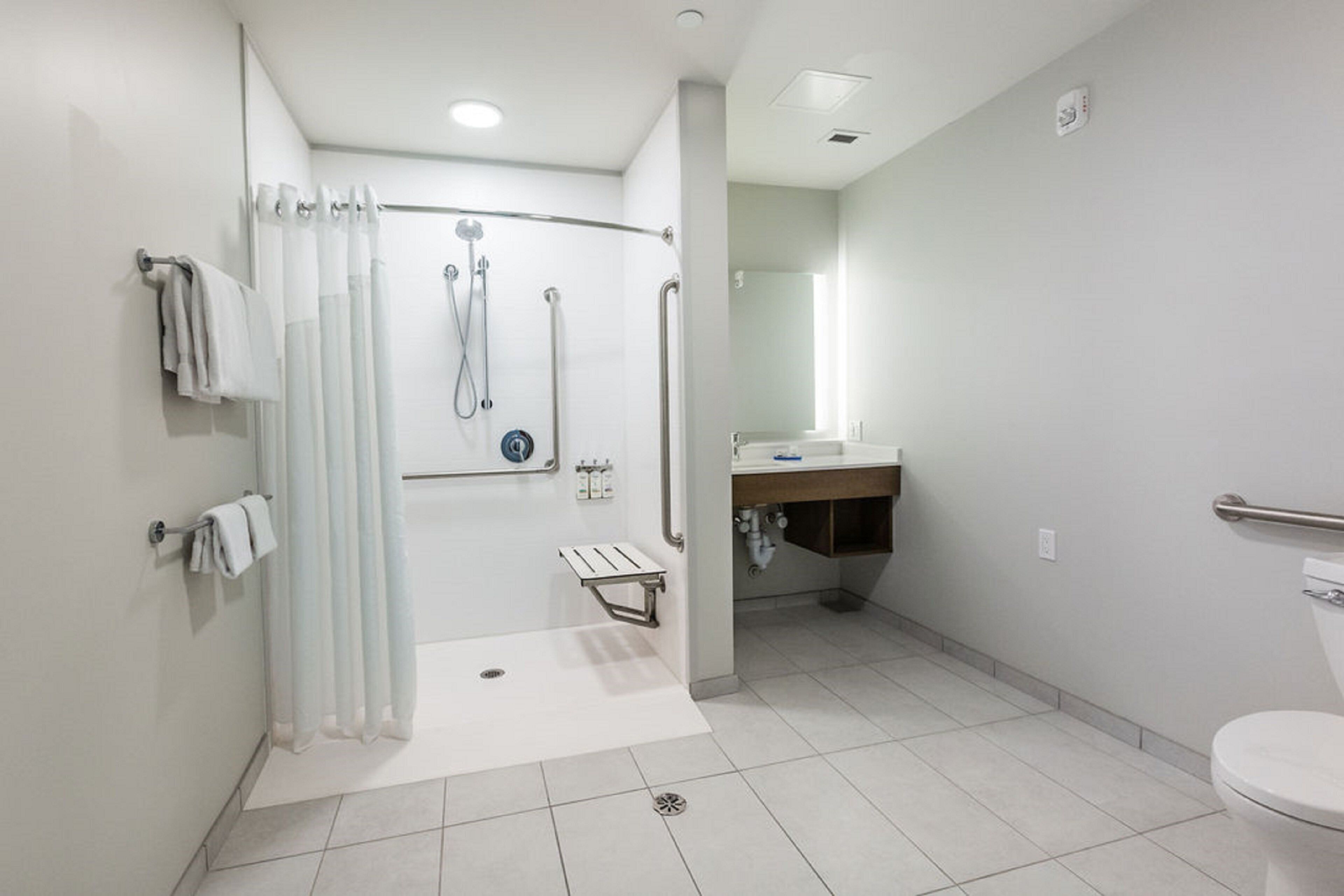 Un baño moderno con ducha a nivel, inodoro y lavabo.