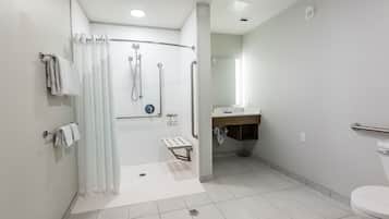 Un baño moderno con ducha a nivel, inodoro y lavabo.