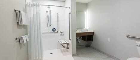 Un baño moderno con ducha a nivel, inodoro y lavabo.