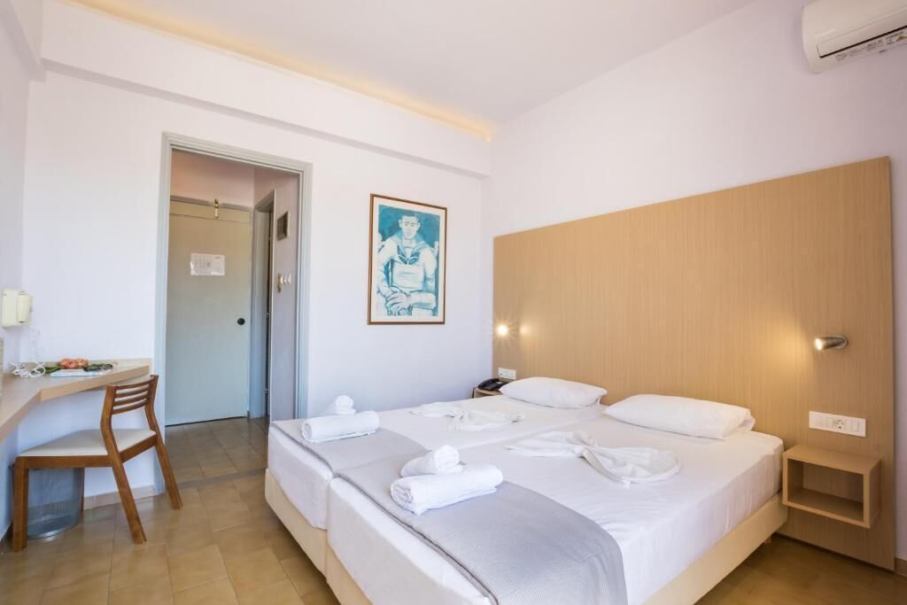 A hotel room with a bed, a desk, and a chair.