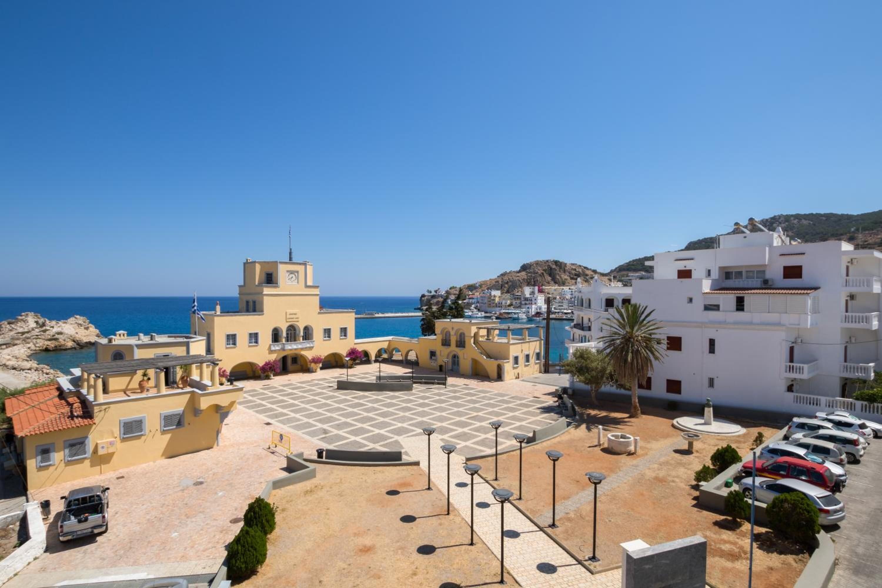 A coastal building with a courtyard, parking area, and a view of the sea.