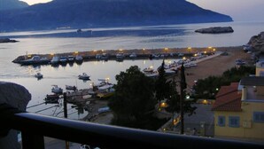 A marina with boats docked, a sandy beach, and a mountainous backdrop. - Atlantis Hotel (Karpathos)
