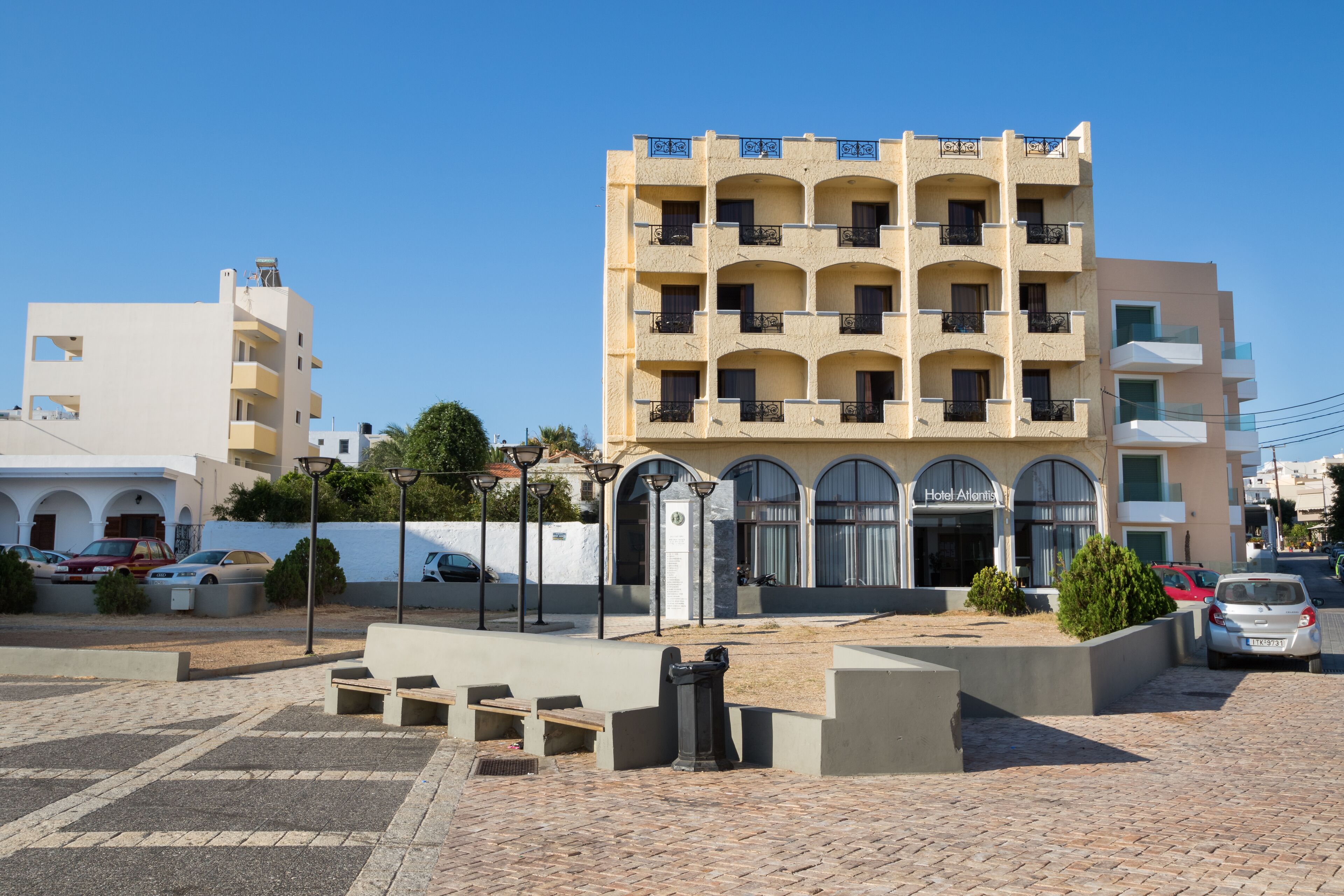 A multi-story hotel with a central courtyard, outdoor seating, and a visible entrance.