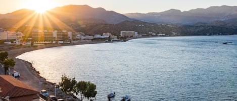 A coastal view with a marina, buildings, and mountains in the background.