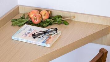 Una bandeja de madera con un libro titulado 'Greekie Pomidor' y un par de gafas, junto con algunas frutas y hojas.