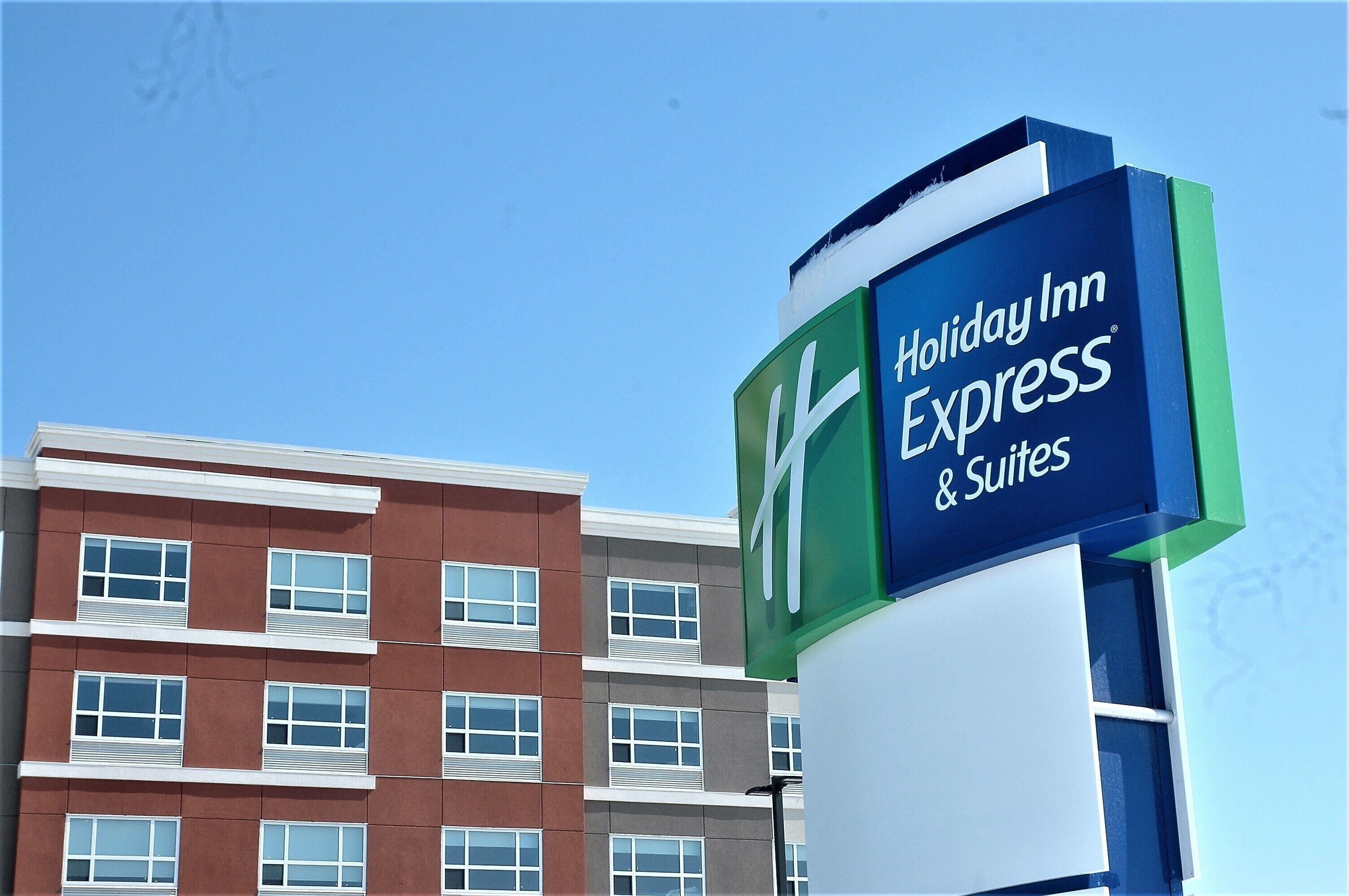 Un letrero de Holiday Inn Express con un edificio moderno al fondo.