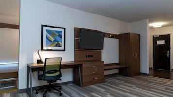 A modern office space with a desk, chair, TV, and storage cabinets.