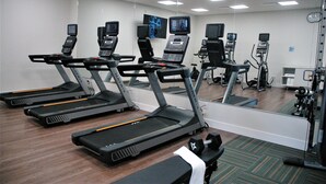 Een fitnessruimte met loopbanden, hometrainers en krachtapparaten.
