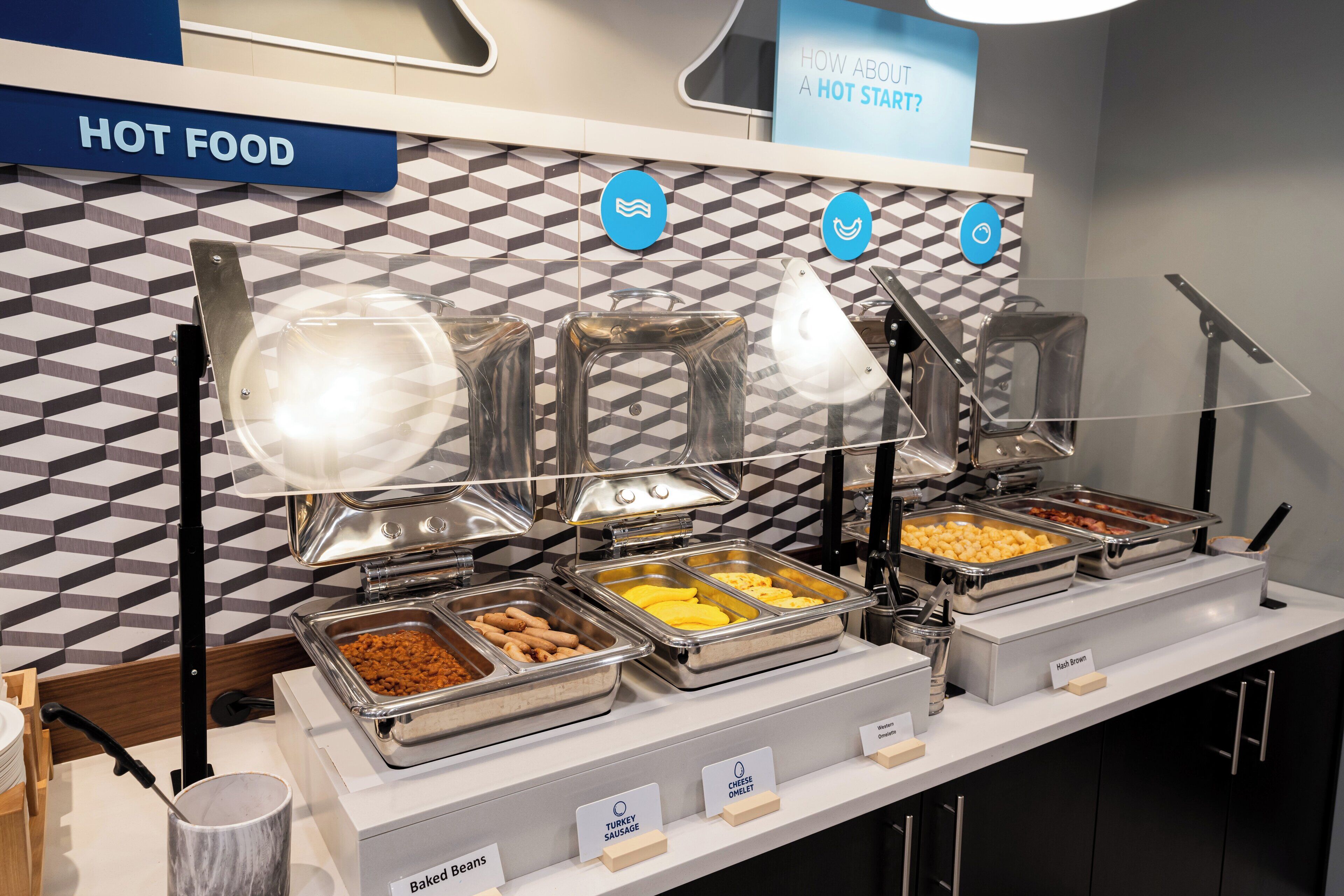A buffet with labeled sections for baked beans, turkey sausage, and cheese omelet.