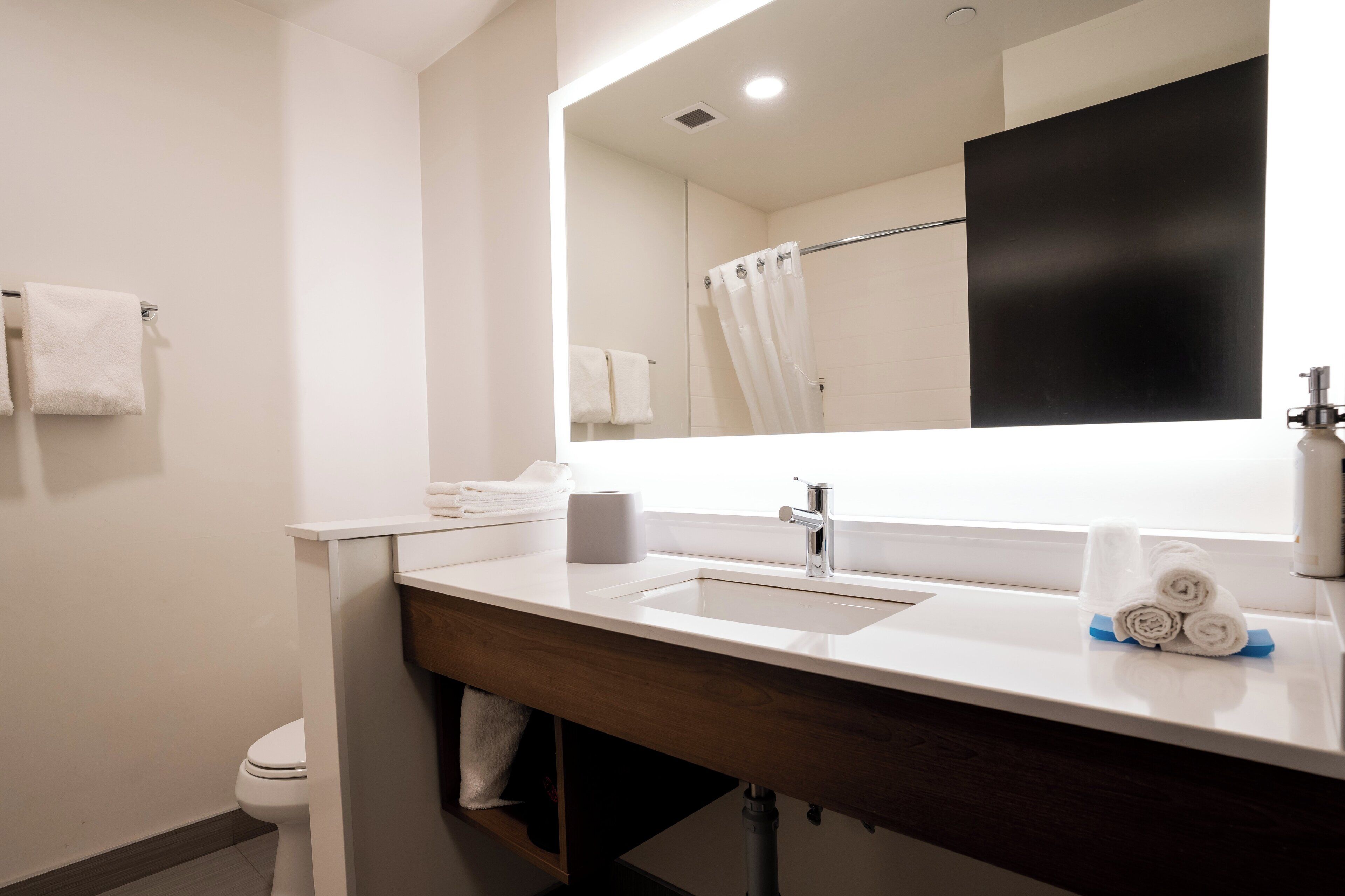 A modern bathroom with a white sink, a mirror, and a towel rack.