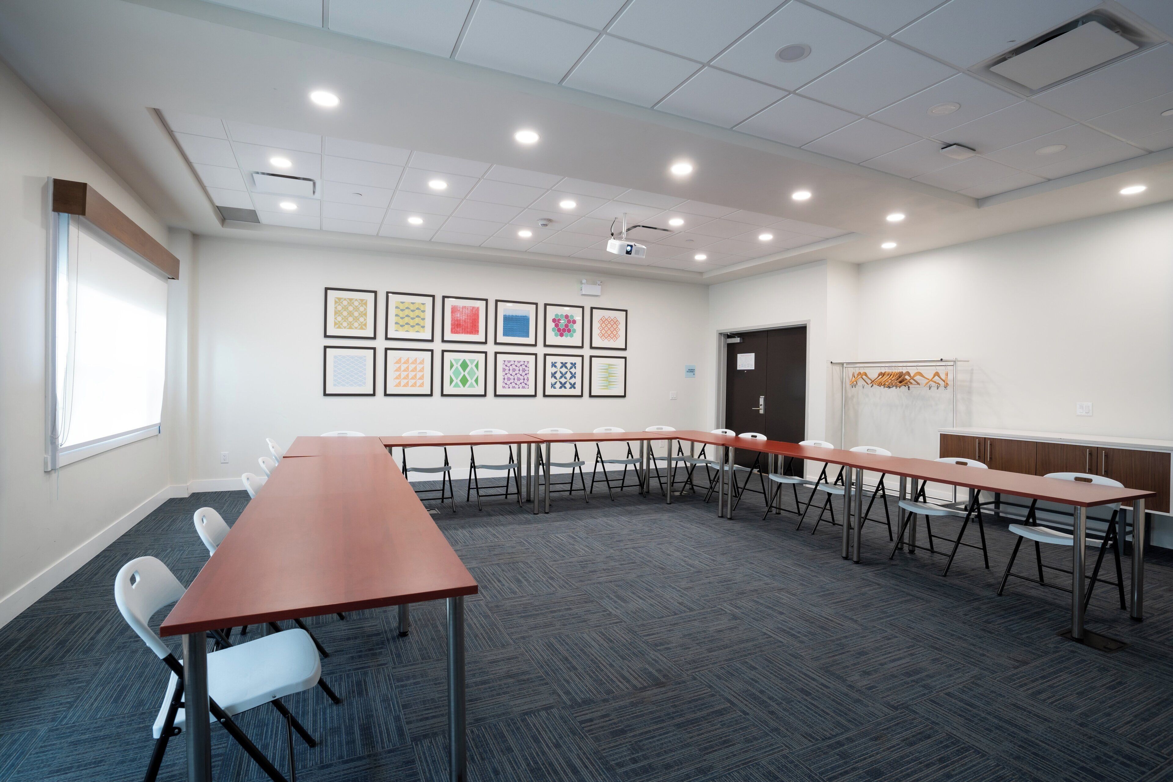 A conference room with a long table, chairs, a projector, and framed artwork on the wall.