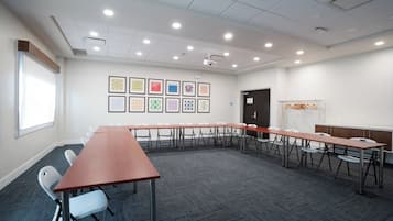 A conference room with a long table, chairs, a projector, and framed artwork on the wall.