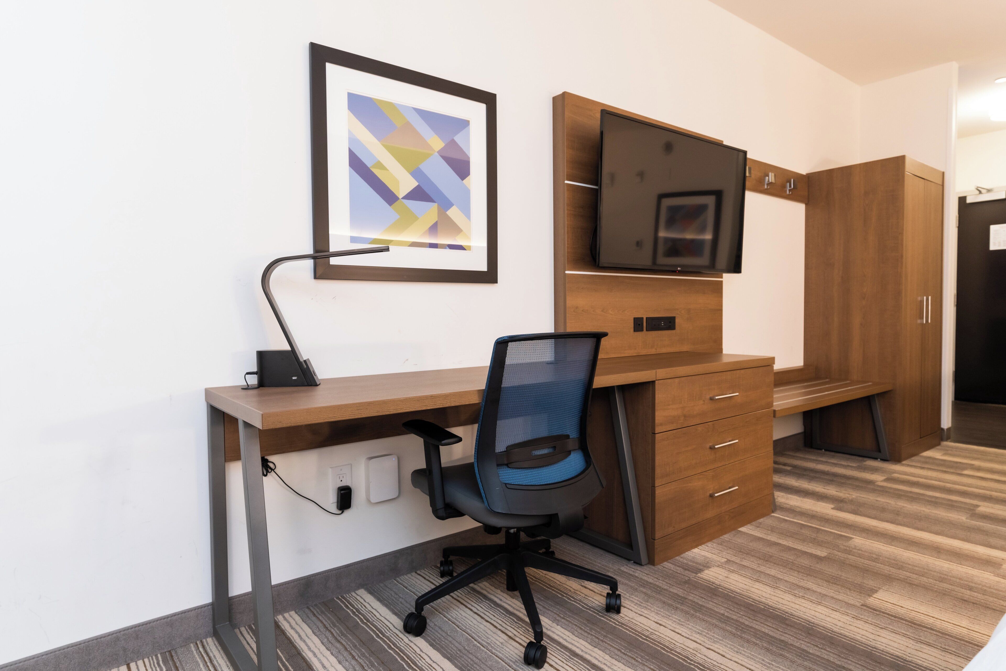Un espacio de oficina moderno con un escritorio, una silla y un televisor montado.
