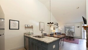 A modern kitchen with granite countertops, a built-in sink, and a dining area with a wooden table and chairs.