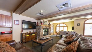 A living room with a fireplace, leather sofas, a flat-screen TV, and wooden cabinets.