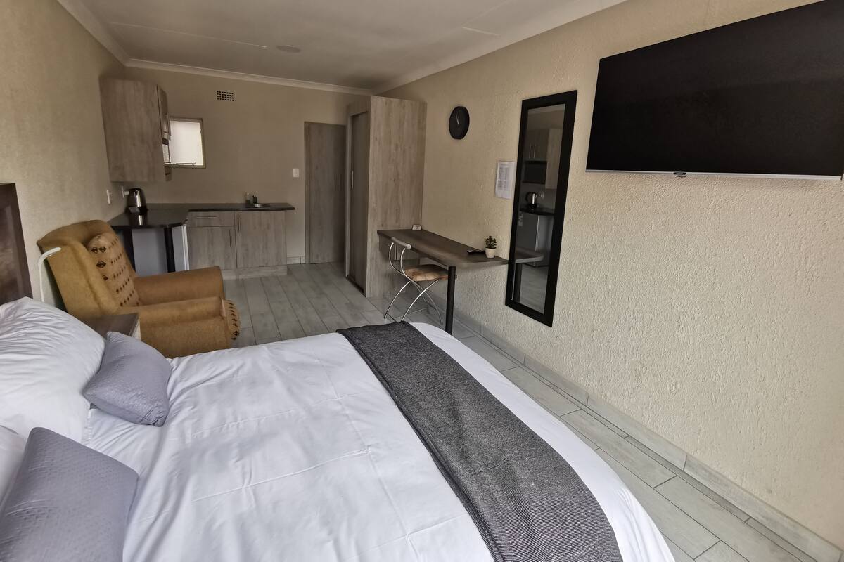 Una habitación de hotel con cama, escritorio y kitchenette.