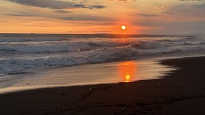 Una spiaggia al tramonto con le onde che si infrangono sulla riva e un cielo sereno.