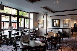 A restaurant with wooden tables and chairs, large windows, and framed pictures on the walls. - Furness Railway by Wetherspoon (Barrow-in-Furness)