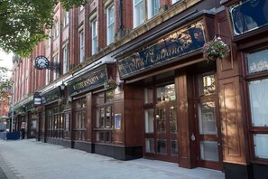 A row of traditional brick buildings with large windows and hanging flower baskets. - Furness Railway by Wetherspoon (Barrow-in-Furness)
