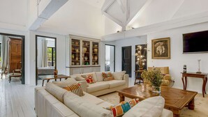 Un salón espacioso con un sofá grande, una mesa de centro y un aparador lleno de objetos decorativos.