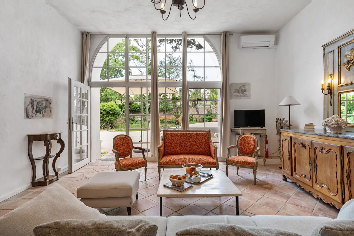 Un salón amplio con un gran ventanal, un televisor y una mesa de comedor con una cesta y una taza.