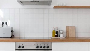 Una cocina moderna con campana extractora de acero inoxidable, horno empotrado y encimera de madera.