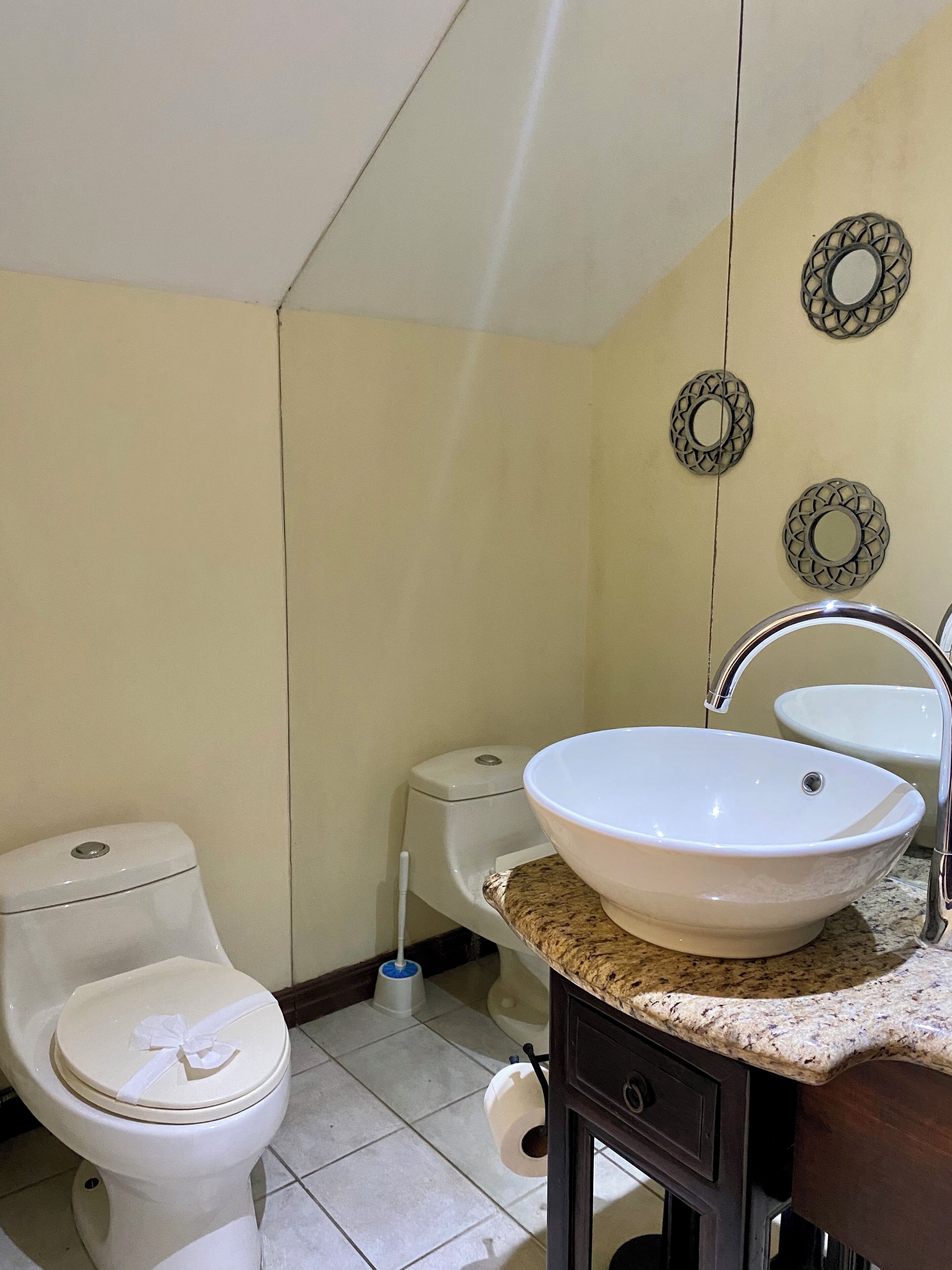 Een badkamer met toilet, bidet, wastafel en decoratieve wandplaten.