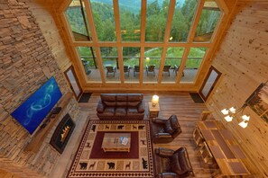 Relax in a cozy cabin with a fireplace, leather sofa, and panoramic forest views.