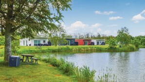 Um terreno à beira do lago com cabanas modernas, uma mesa de piquenique e um pequeno cais.