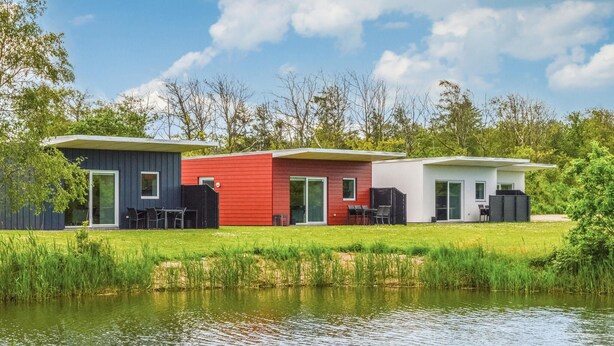 Três cabanas modernas junto a um lago, com área de estar externa e gramado.