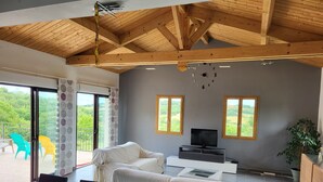 A modern living room with a wooden ceiling, a TV, and a covered sofa. - Entire villa 230 m2 with magnificent view (Blars)