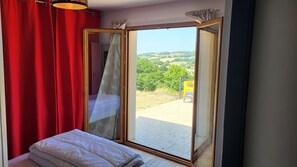 Quarto com uma grande porta de vidro que se abre para uma varanda.