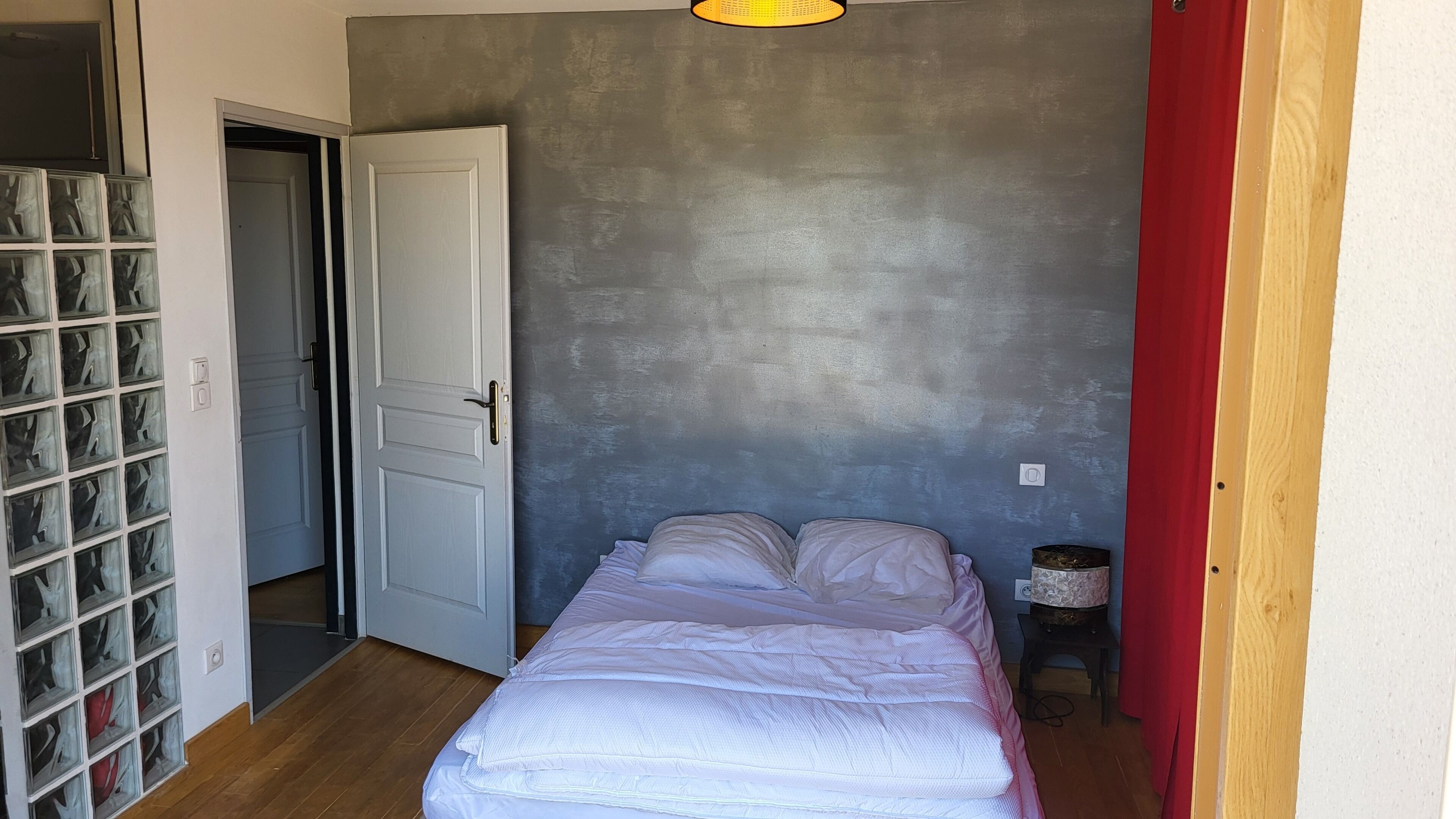 A bedroom with a bed, a door, and a wall with a textured finish.