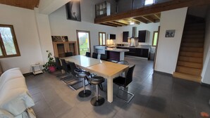 A spacious living area with a dining table, chairs, and a sofa. A kitchen with modern appliances is visible in the background. - Entire villa 230 m2 with magnificent view (Blars)