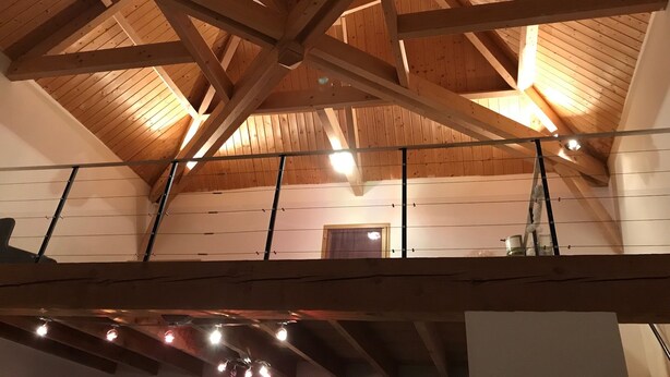 A high ceiling with wooden beams and a sloped roof, a ladder, and a door in the background. - Entire villa 230 m2 with magnificent view (Blars)
