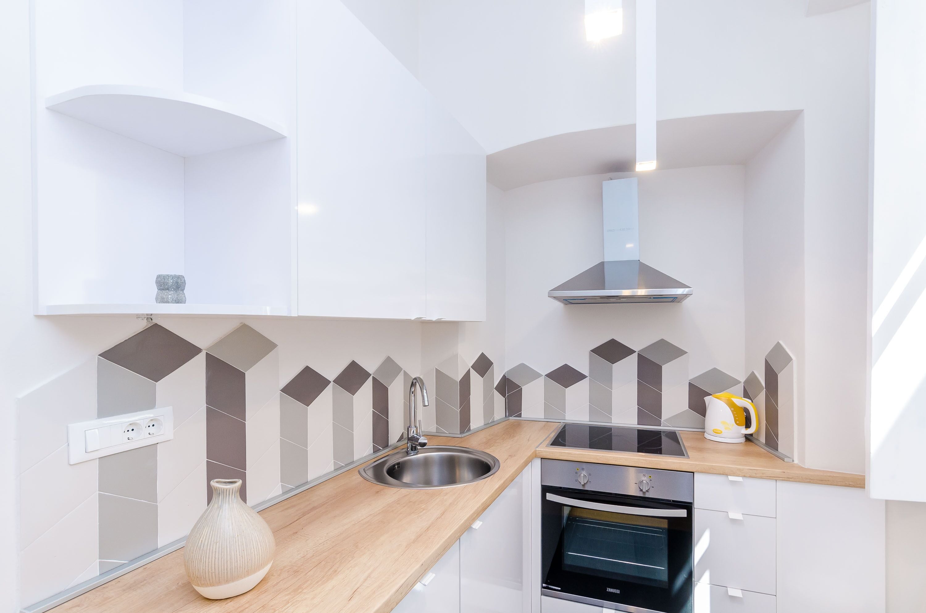 A modern kitchen with a stainless steel sink, a built-in oven, and a range hood.