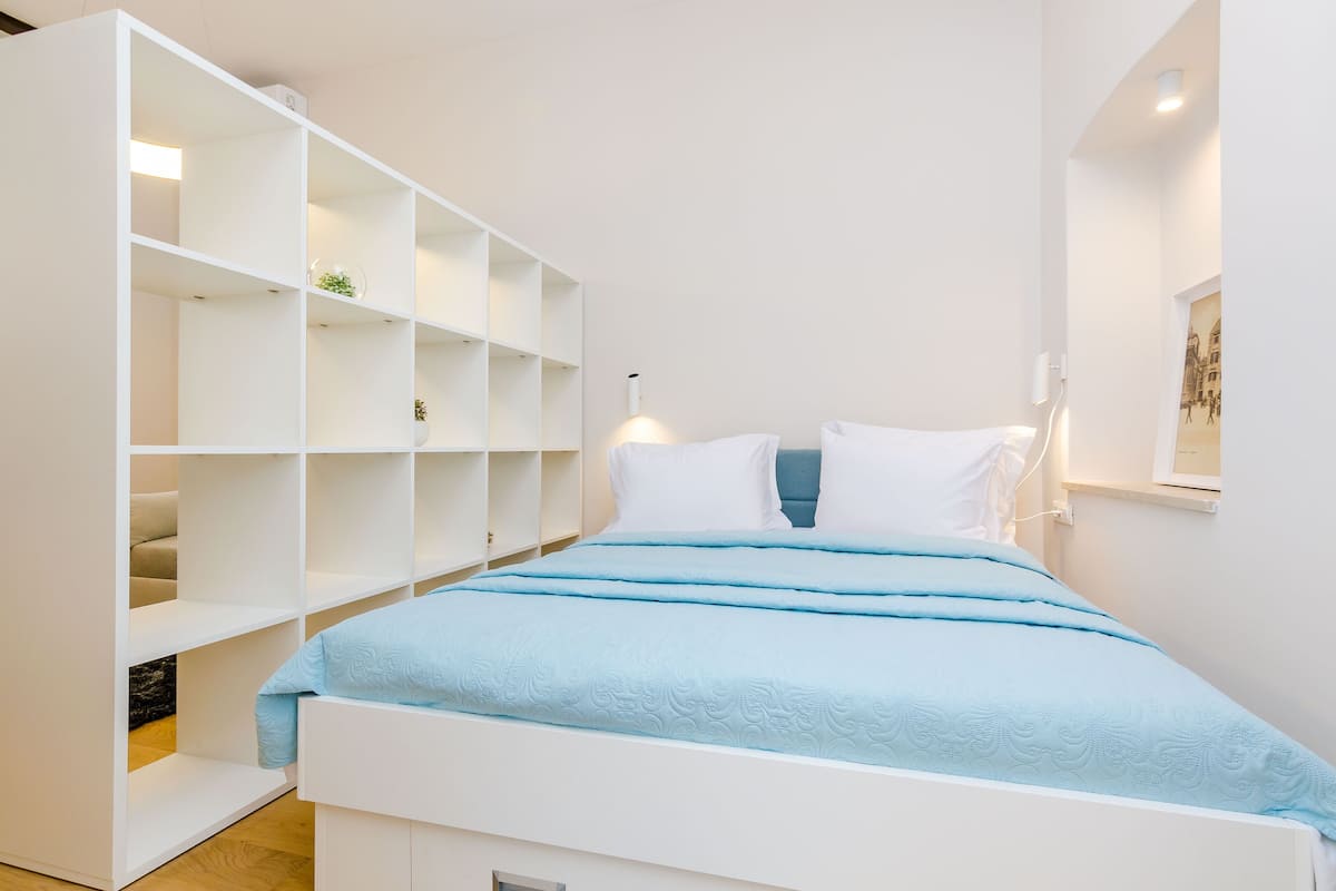 Ein Schlafzimmer mit einem Bett, einem weißen Regal und einer Wandleuchte.