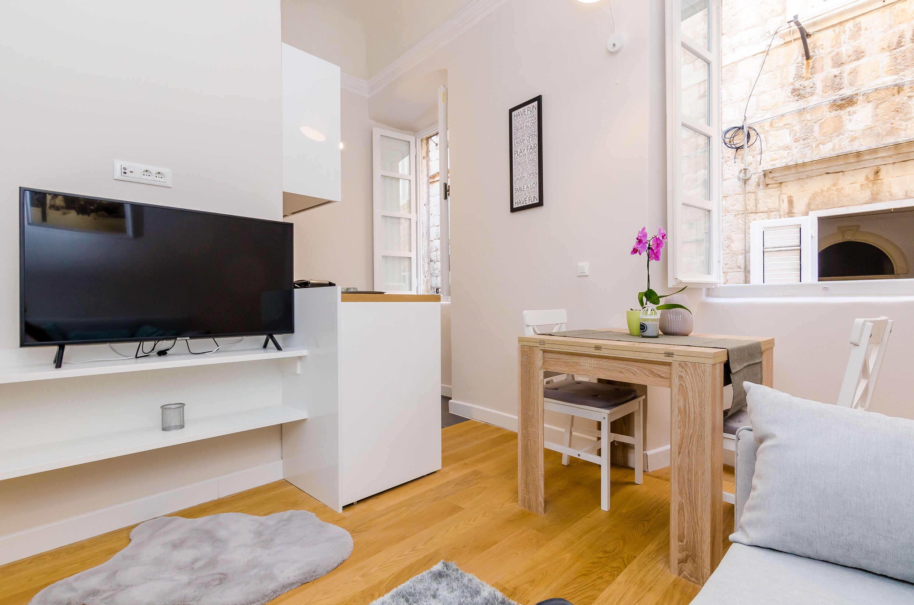 Een moderne woonkamer met een flatscreen televisie, houten meubels en een stenen muur.