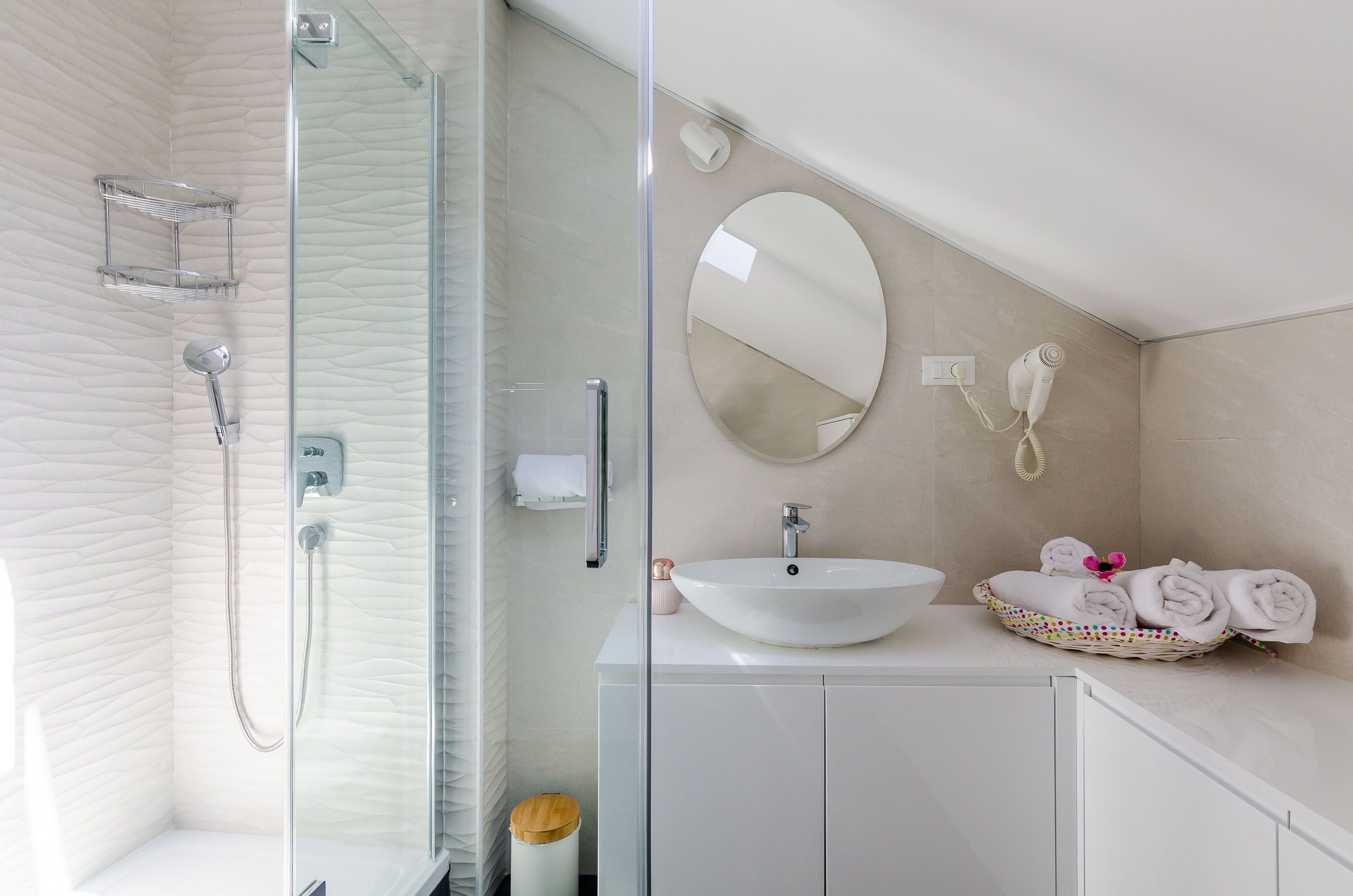 A modern bathroom with a glass-enclosed shower, a white sink, and a mirror.