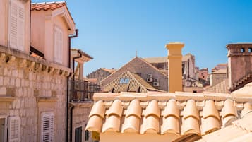 Un edificio tradizionale in pietra con tetto in tegole e persiane bianche.