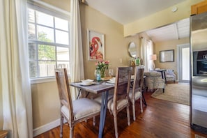 Enjoy meals in this stylish dining area with a wooden table, chairs, and a beautiful painting.