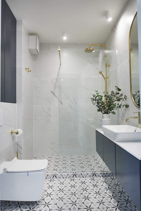 Un baño moderno con cabina de ducha, dos lavamanos y un inodoro.